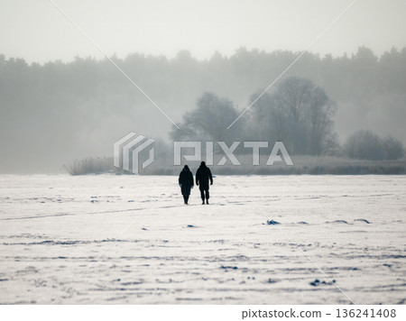 Two people walking in the snow 136241408