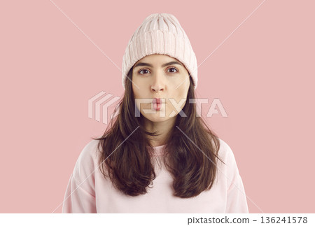 Portrait of funny young fashion model in pastel pink winter hat puckering her lips 136241578