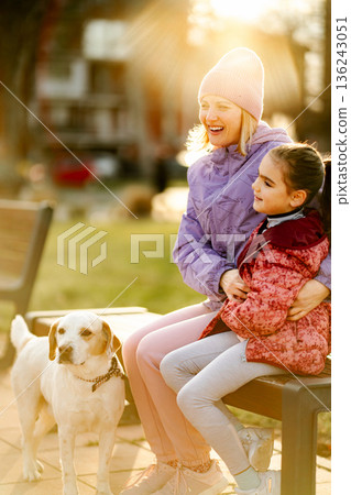 Mother and daughter enjoying golden hour with dog 136243051
