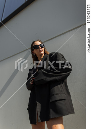 Confident woman in fashionable streetwear style, sunglasses and oversized blazer. Modern urban fashion photography. Confident woman in fashionable streetwear style, sunglasses and oversized blazer. Modern urban fashion photography. 136243273