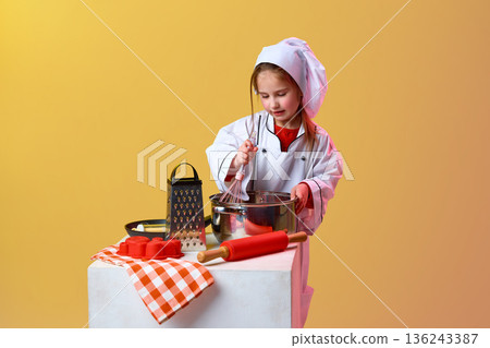 Young girl chef cooking with kitchen tools in studio. Young girl chef cooking with kitchen tools in studio. 136243387