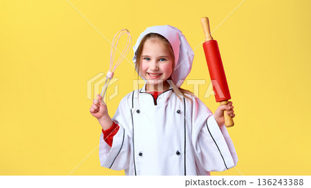 Child dressed as chef holding whisk and rolling pin. Child dressed as chef holding whisk and rolling pin. 136243388