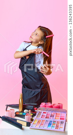 Young makeup artist using hair rollers during styling session. 136243395