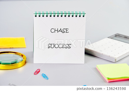 White notepad displays Chase Success message on a gray desk. Nearby are a calculator, magnifying glass, paper clips, and sticky notes 136243598