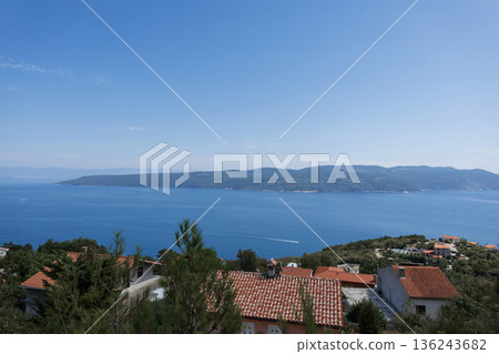 Panoramic view of Croatian coastline with turquoise sea and village rooftops. Summer vacation and travel background. Peaceful seascape with gentle waves and wide horizon under a clear sky in Croatia. 136243682