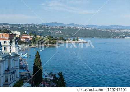 Coastal view of Opatija, Croatia with historic architecture, blue Adriatic Sea, beaches, and distant mountains. Popular Mediterranean travel and holiday destination. 136243701