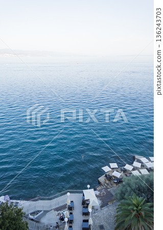 Aerial view of Opatija, Croatia, with turquoise Adriatic Sea, swimmers, beach umbrellas, and a scenic coastline. Popular summer travel destination on the Croatian Riviera. Summer luxury rest Aerial view of Opatija, Croatia, with turquoise Adriatic Sea, swimmers, beach umbrellas, and a scenic coastline. Popular summer travel destination on the Croatian Riviera. Summer luxury rest 136243703