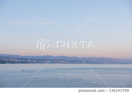 Coastal view of Opatija, Croatia, with calm Adriatic Sea and mountains in soft pastel evening light. Scenic seascape of Opatija, Croatia, city by the Adriatic Sea with distant hills and serene water. Coastal view of Opatija, Croatia, with calm Adriatic Sea and mountains in soft pastel evening light. Scenic seascape of Opatija, Croatia, city by the Adriatic Sea with distant hills and serene water. 136243709
