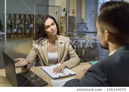 Financial advisor consulting client in office, reviewing documents and options Financial advisor consulting client in office, reviewing documents and options 136244079