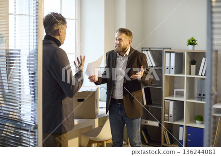 Angry boss confronting employee in office, arguing over report and results Angry boss confronting employee in office, arguing over report and results 136244081