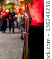 Detailed view of a hand holding a large lit candle in a religious procession 136244238