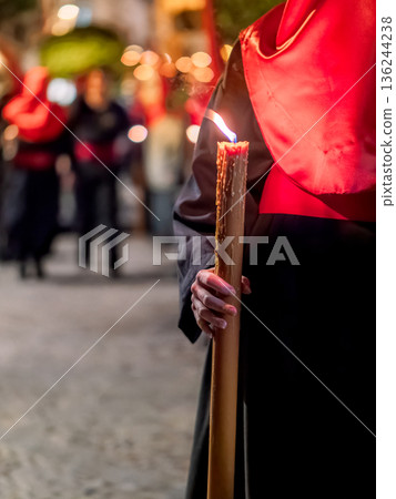 Detailed view of a hand holding a large lit candle in a religious procession Detailed view of a hand holding a large lit candle in a religious procession 136244238