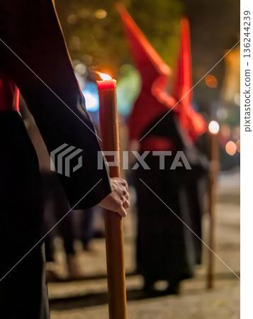 Detailed view of a hand holding a large lit candle in a religious procession Detailed view of a hand holding a large lit candle in a religious procession 136244239