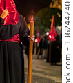 Detailed view of a hand holding a large lit candle in a religious procession 136244240