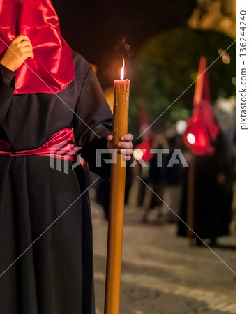 Detailed view of a hand holding a large lit candle in a religious procession Detailed view of a hand holding a large lit candle in a religious procession 136244240