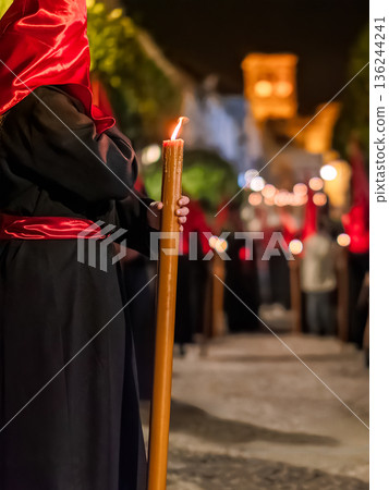 Detailed view of a hand holding a large lit candle in a religious procession Detailed view of a hand holding a large lit candle in a religious procession 136244241