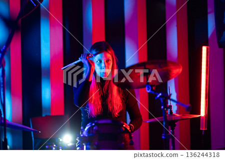 Woman drummer performing live with colorful stage lighting Woman drummer performing live with colorful stage lighting 136244318