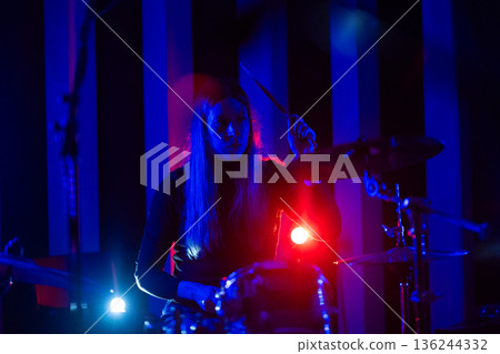 Drummer playing music during dynamic live concert performance 136244332
