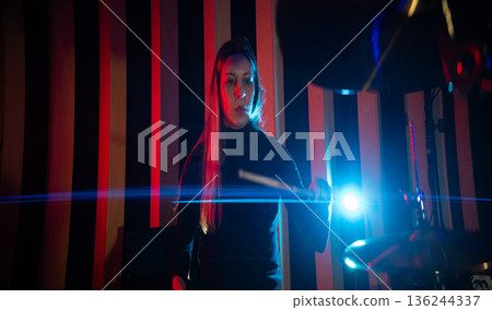 Female drummer playing cymbal in vibrant studio light Female drummer playing cymbal in vibrant studio light 136244337