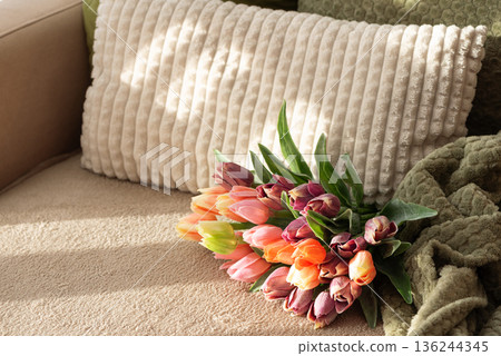 Tulip Bouquet and Gift Box on Cozy Sofa. Warm Spring Flatlay with Soft Textures Tulip Bouquet and Gift Box on Cozy Sofa. Warm Spring Flatlay with Soft Textures 136244345