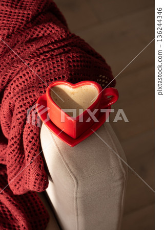 Heart Shaped Coffee Cup on Armchair with Red Blanket. Cozy Valentines Day Still Life Heart Shaped Coffee Cup on Armchair with Red Blanket. Cozy Valentines Day Still Life 136244346