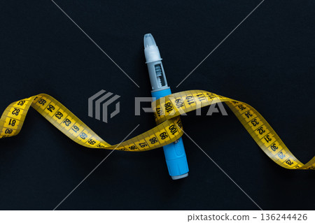 Drug injection ozempic with a yellow tape measure on a black background. Ozempic Insulin injection pen or insulin cartridge pen for diabetics. Medical equipment for diabetes parients. 136244426