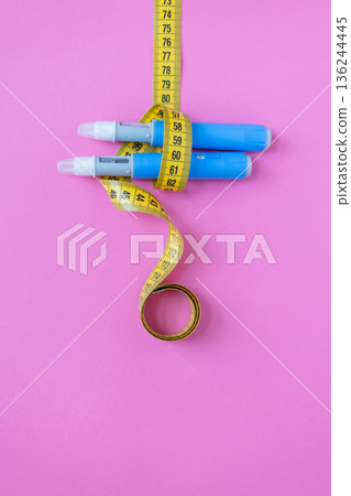 Medical weight loss concept with insulin pens and measuring tape on colorful pink background, symbolizing treatment, diabetes, and obesity control. drugs injection ozempic for weight loss Medical weight loss concept with insulin pens and measuring tape on colorful pink background, symbolizing treatment, diabetes, and obesity control. drugs injection ozempic for weight loss 136244445