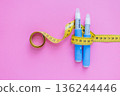 Diabetes medication and weight loss measurement tools on pink background, featuring insulin injection pens and yellow tape measure. drugs injection ozempic for weight loss 136244446