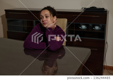 Thoughtful Woman At Dining Table In Modern Kitchen, Quiet Moment Of Reflection 136244485