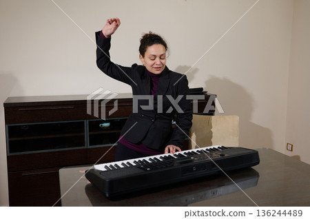 Professional Woman In Suit Plays Keyboard At Office Desk, Expressing Joy And Focus 136244489