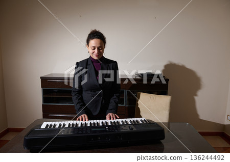 Businesswoman Plays Keyboard At Desk In Modern Home Office Studio Setting For Creative Music Businesswoman Plays Keyboard At Desk In Modern Home Office Studio Setting For Creative Music 136244492