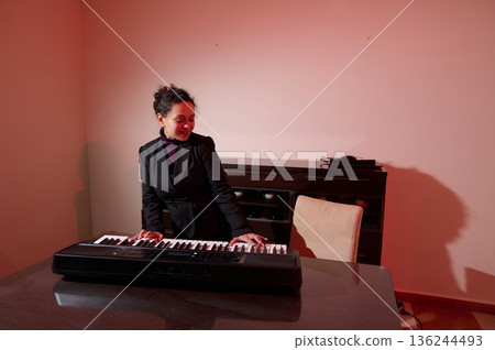 Professional Woman In Blazer Plays Keyboard In Modern Office With Warm Pink Lighting 136244493