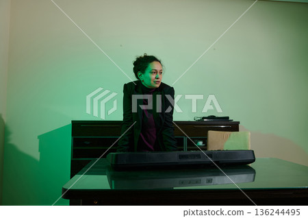 Business Woman At Keyboard In Green Lit Office Setting With Desk And Console 136244495
