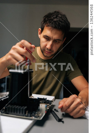 Vertical shot of serious computer technician carefully installing CPU cooler onto motherboard, performing essential maintenance and upgrades on desktop computer for improved performance, reliability Vertical shot of serious computer technician carefully installing CPU cooler onto motherboard, performing essential maintenance and upgrades on desktop computer for improved performance, reliability 136244568
