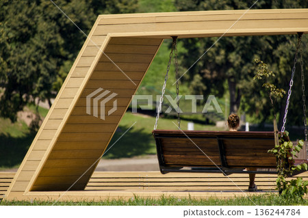 Peaceful Park Setting With Wooden Swings And Shaded Greenery Peaceful Park Setting With Wooden Swings And Shaded Greenery 136244784