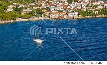 White sailboat on calm Adriatic waters near coastal town in Croatia summer scene aerial view 136245023