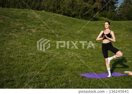 Practicing yoga in a sunny green park during a tranquil afternoon 136245641