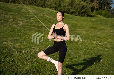 Relaxing yoga practice in a peaceful park setting on a sunny afternoon 136245642