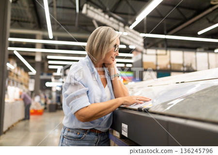 Middle-aged woman shopping for art supplies in a well-lit store during the day 136245796