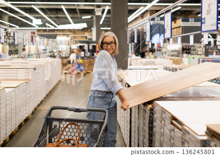 Elderly woman shopping for flooring materials in a home improvement store during a busy afternoon Elderly woman shopping for flooring materials in a home improvement store during a busy afternoon 136245801