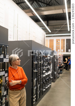Woman shopping for home improvement items in a modern hardware store with a wide selection of tools Woman shopping for home improvement items in a modern hardware store with a wide selection of tools 136245803