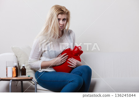 Woman feeling stomach cramps sitting on cofa 136245844