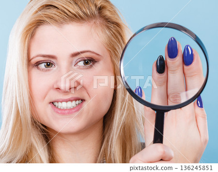 Woman looking at nails through magnifying glass 136245851