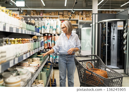 Woman shopping for kitchenware in a modern store, exploring various items and selecting favorites Woman shopping for kitchenware in a modern store, exploring various items and selecting favorites 136245905