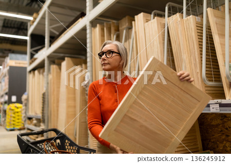 Woman shopping for wooden panels in a home improvement store during the daytime 136245912