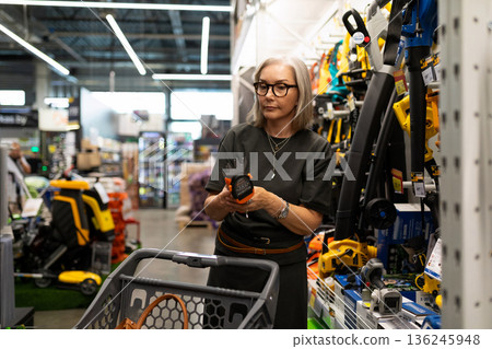 Shopping for tools and equipment in a hardware store during the afternoon with a focused elderly Shopping for tools and equipment in a hardware store during the afternoon with a focused elderly 136245948