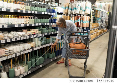 Shopping for home decor items in a store aisle filled with colorful accessories and candles 136245950