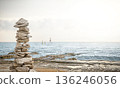 A stone pyramid of flat stones on a rocky seashore. 136246056