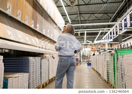 Woman shopping for home improvement materials in a large warehouse store during the day Woman shopping for home improvement materials in a large warehouse store during the day 136246064