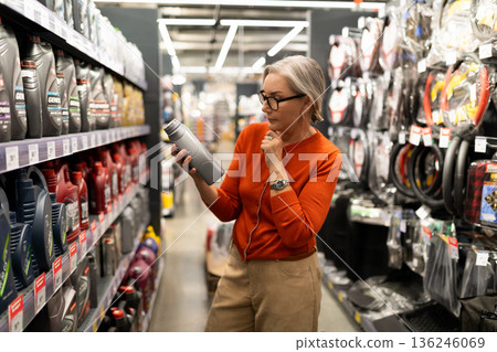 Choosing the right product in a well-stocked hardware store while considering options carefully Choosing the right product in a well-stocked hardware store while considering options carefully 136246069